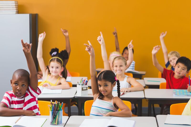 kids raising hands in a classroom